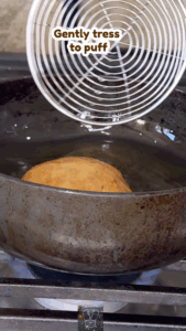 Golden puffed poori being flipped in oil